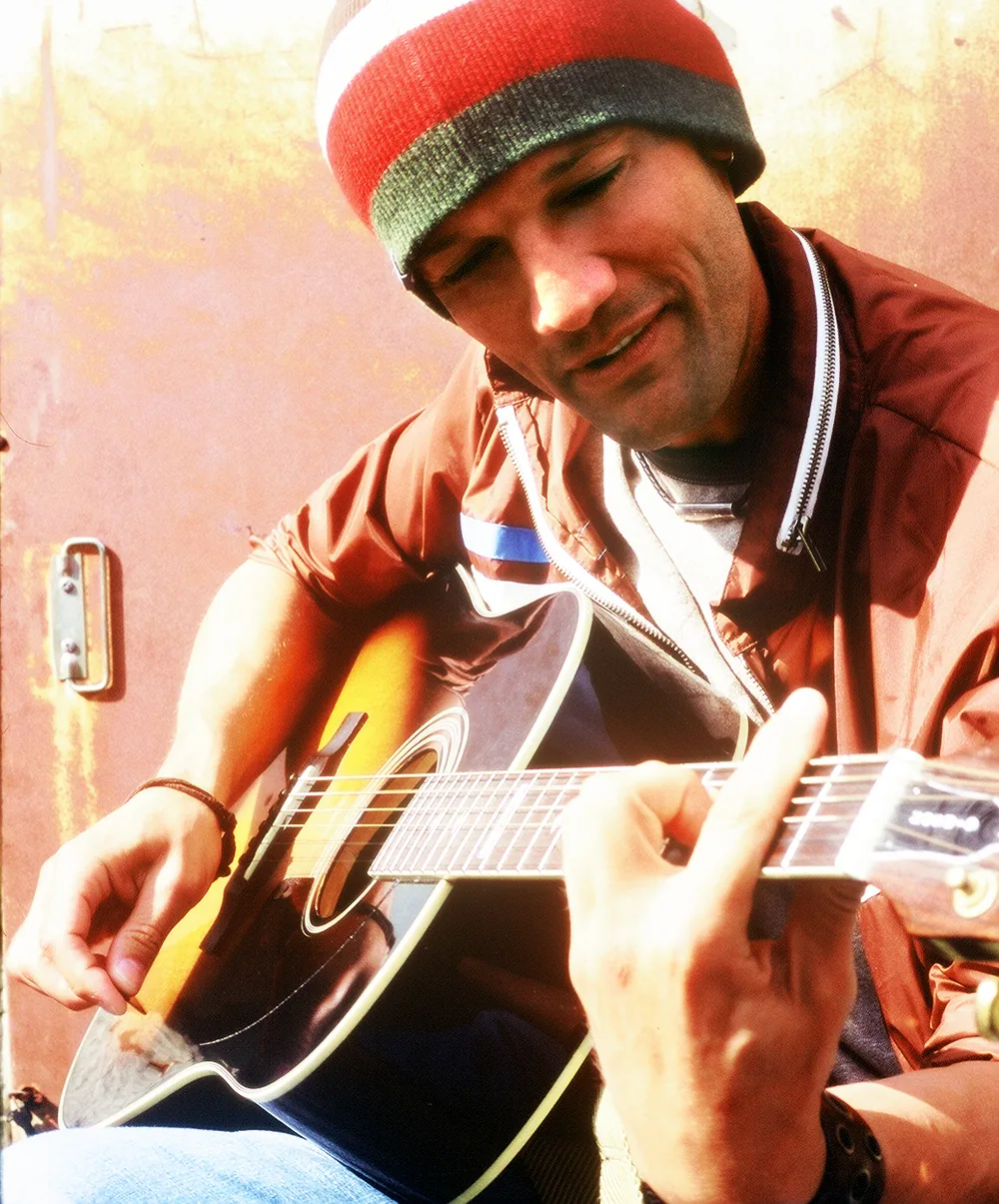 Close-up of Kef strumming an acoustic guitar