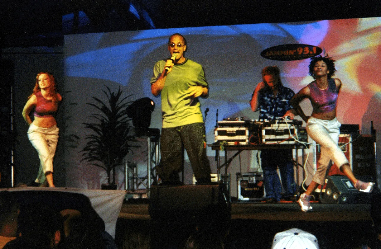 Kef performing on an outdoor stage with two dancers and a DJ