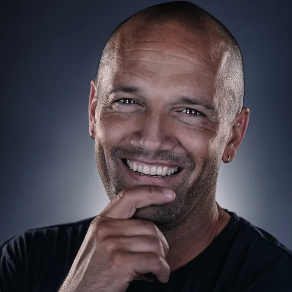 Dave Keffer smiling, hand at his chin, in a black T-shirt against a dark backdrop