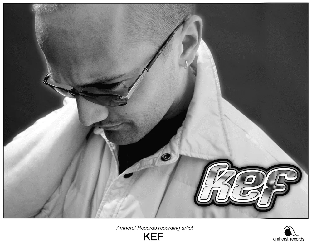 Black-and-white close-up of Kef in glasses looking down