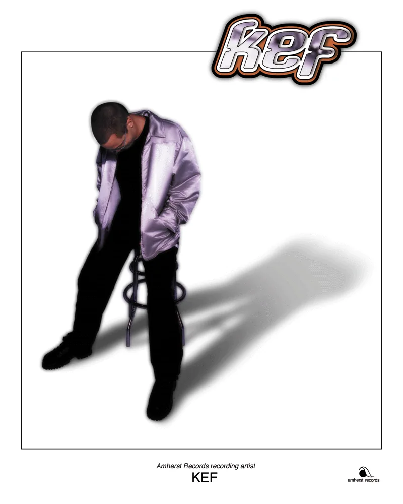 Kef in a shiny jacket leaning on a stool, with the kef logo